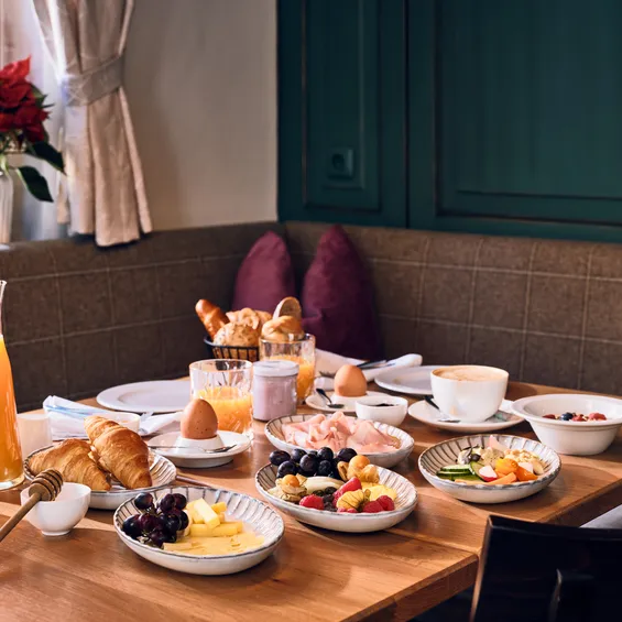 Cozy hotel breakfast table with croissants, fruit, cheese, juice, and coffee