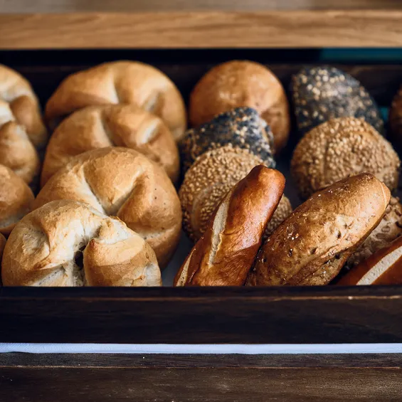 Fresh assortment of German bread rolls in a wooden tray at a bakery