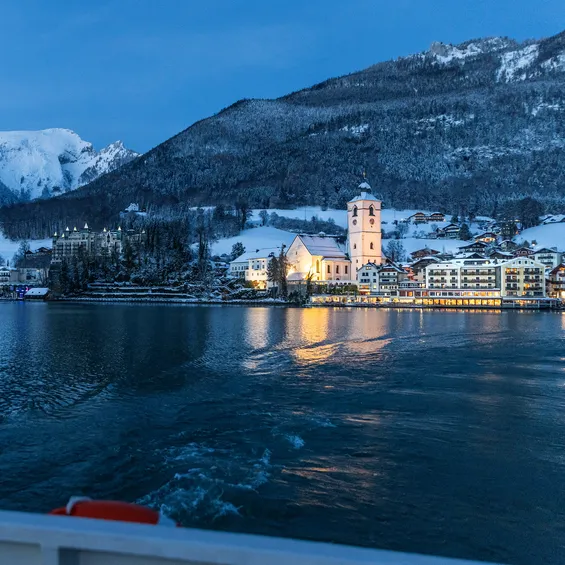 Winter evening view of St. Wolfgang village on Lake Wolfgang with Austrian flag on boat