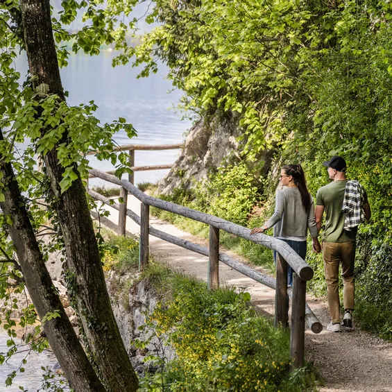 Paar spaziert auf einem malerischen Waldweg am See im Frühling