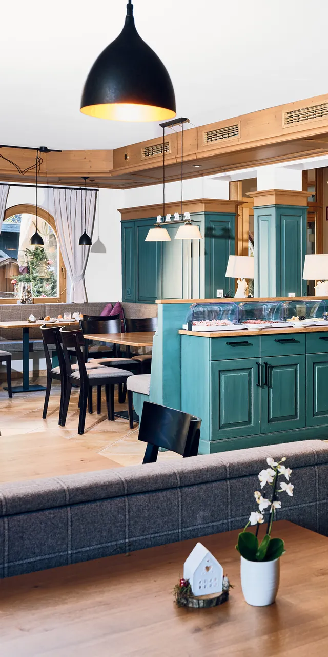 Gemütliches Hotel-Frühstücksbuffet mit grünen Holztresen und modernen Pendelleuchten