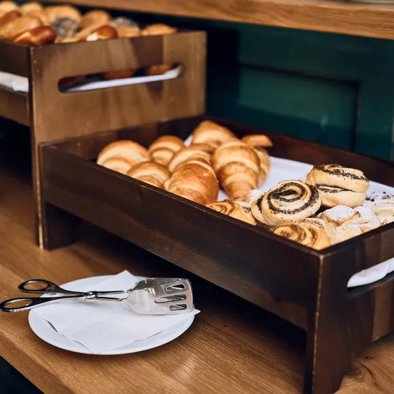 Wooden tray with assorted fresh pastries including croissants and poppy seed rolls