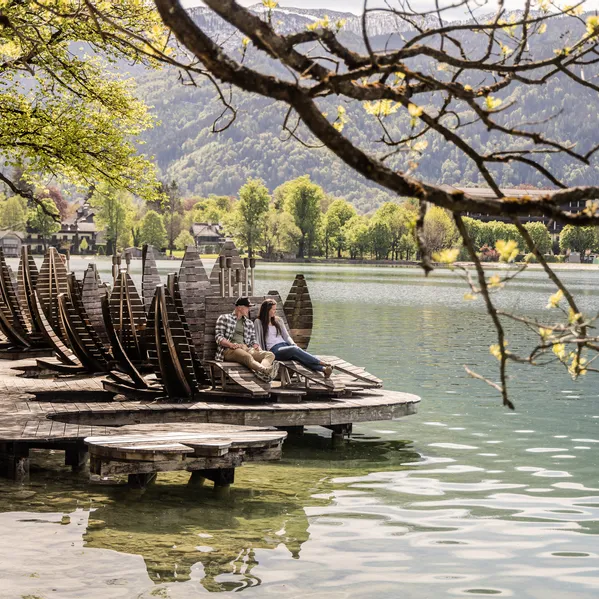 Paar entspannt auf Holzliegen am malerischen See in alpiner Landschaft