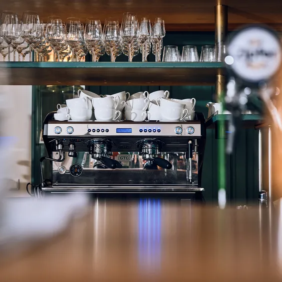 Professional espresso machine with stacked white cups in a modern cafe bar