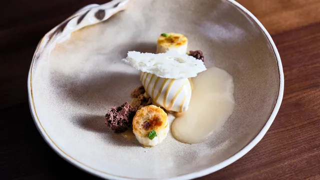 Gourmet-Dessert mit Eiscreme, Bananenscheiben, Schokoladencrumble und weißem Tuile angerichtet