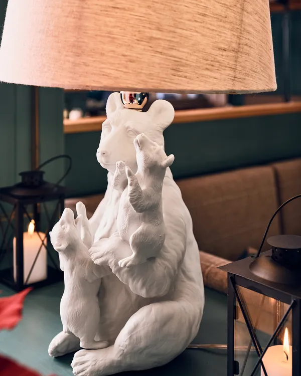 Cozy table lamp with white bear sculpture base and animal figures in soft indoor lighting