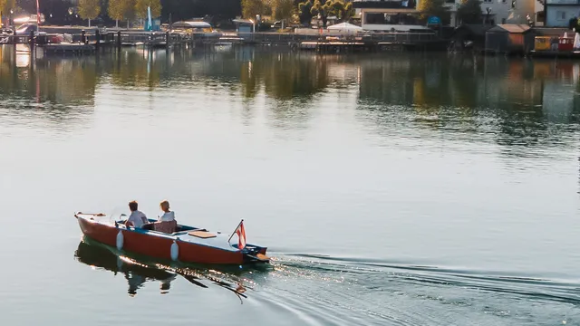 Couple in a small boat on clear alpine lake near picturesque Austrian village and mountains
