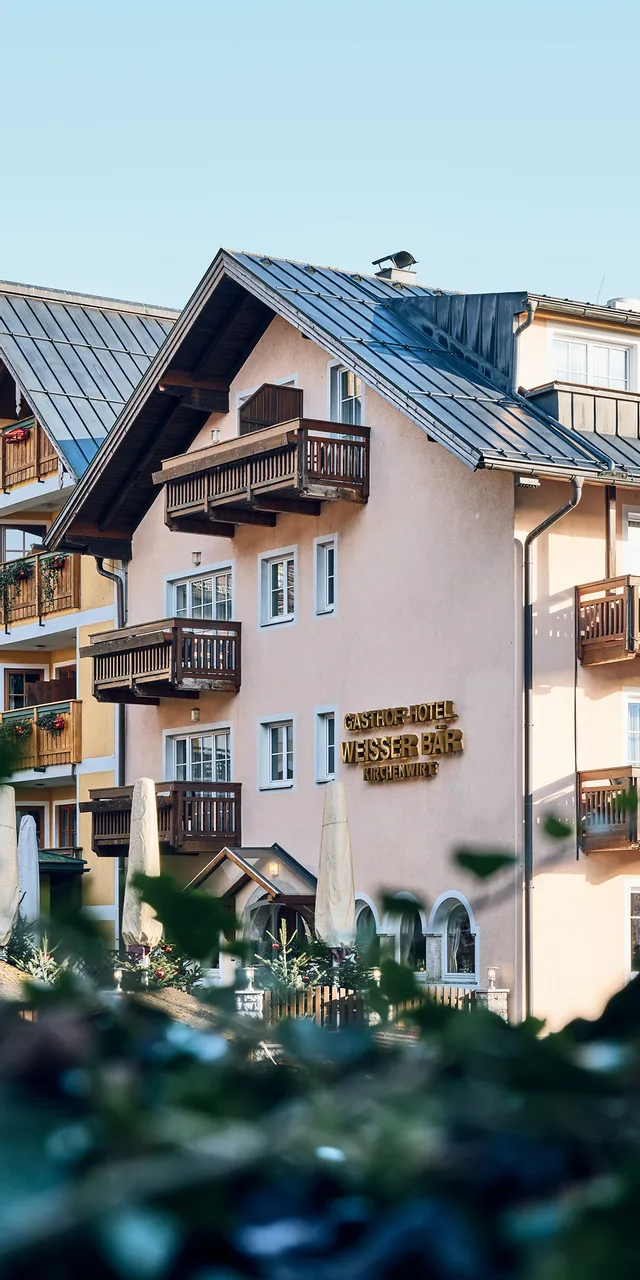 Traditional alpine guesthouse hotel with balconies and wooden roof in a mountain village