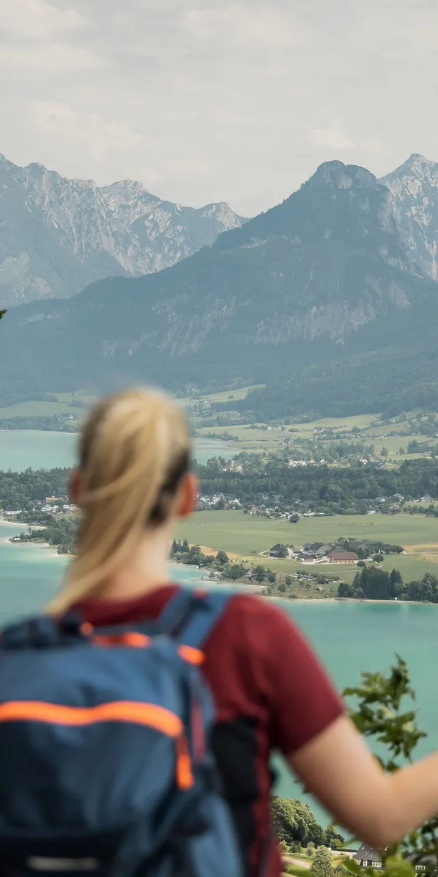Two hikers with backpacks overlooking turquoise lake and alpine mountain landscape