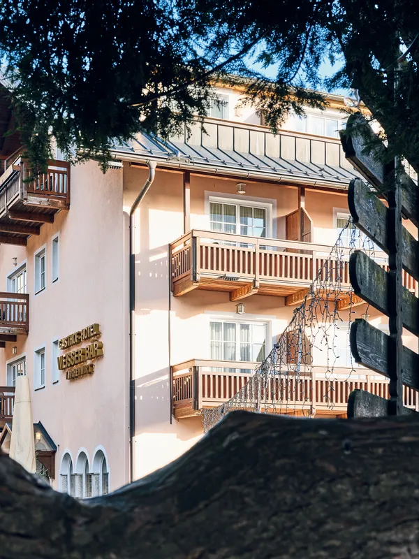 Traditional alpine hotel with wooden balconies framed by tree branches
