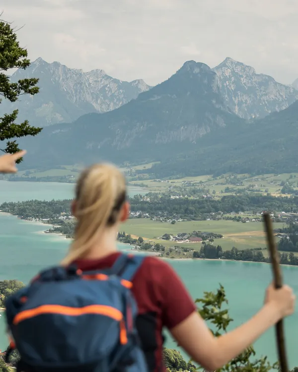 Two hikers with backpacks overlooking turquoise lake and alpine mountain landscape