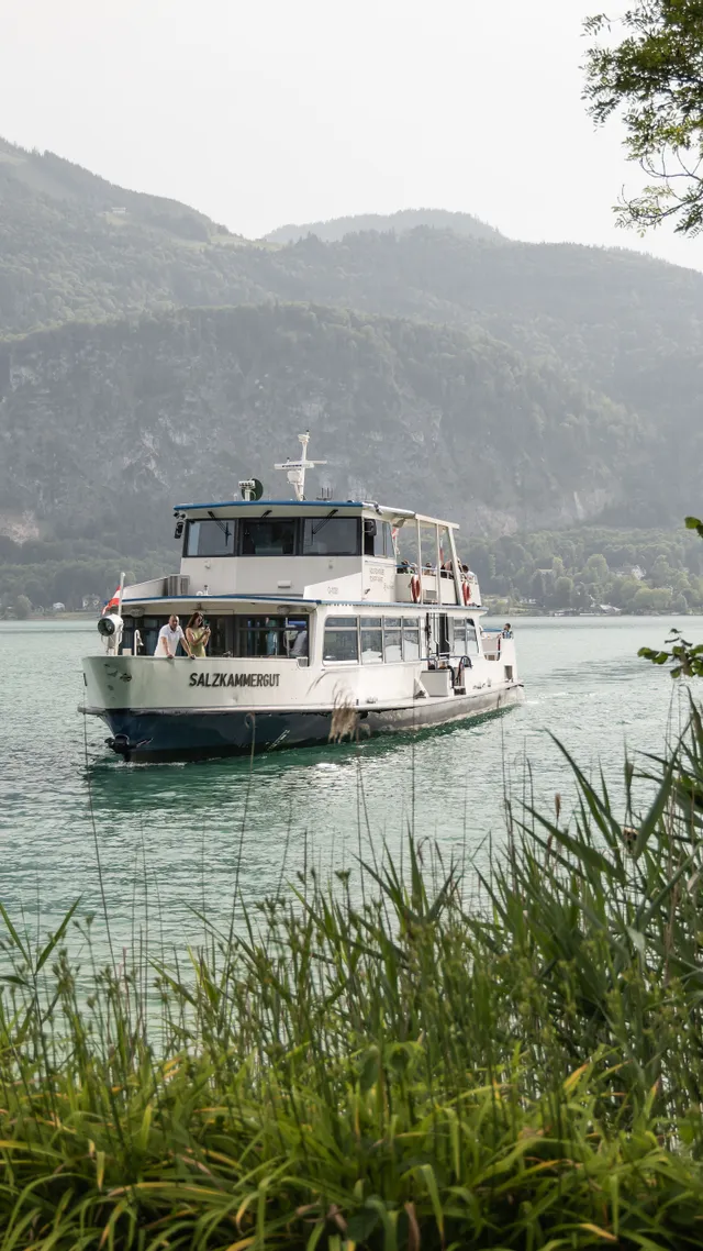Touristenboot Salzkammergut fährt auf einem malerischen See umgeben von Bergen und Grün