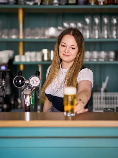 Barkeeperin serviert frisch gezapftes Bier an moderner Bartheke