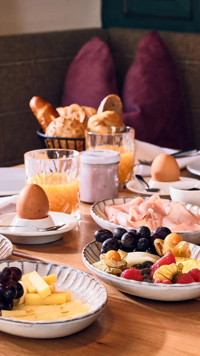 Gemütlicher Hotelfrühstückstisch mit Croissants, Obst, Käse, Saft und Kaffee