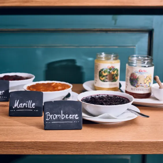 Verschiedene Fruchtmarmeladen und Honig in Schalen und Gläsern auf Holztresen