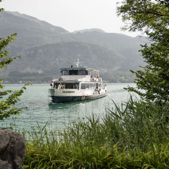 Touristenboot Salzkammergut fährt auf einem malerischen See umgeben von Bergen und Grün