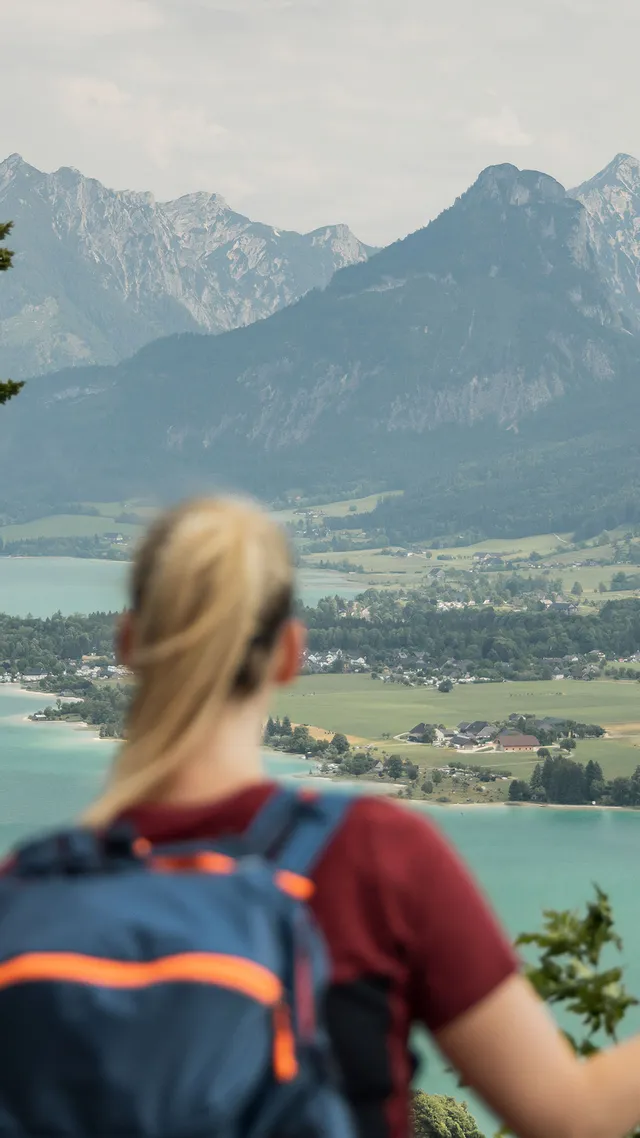 Two hikers with backpacks overlooking turquoise lake and alpine mountain landscape