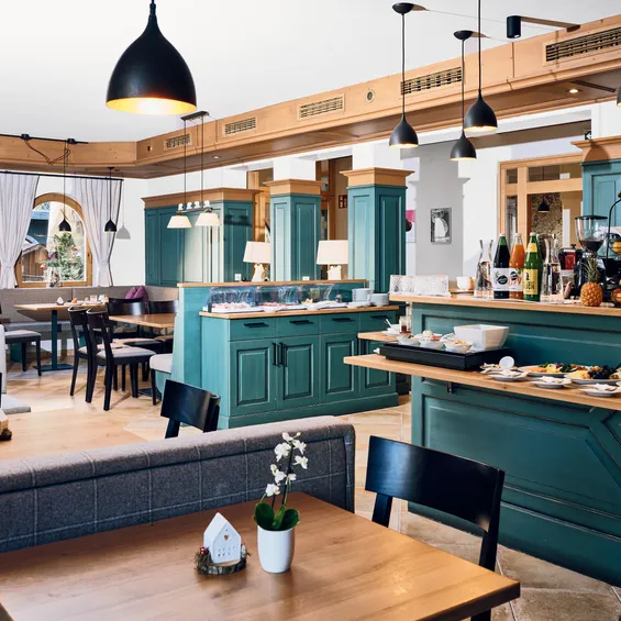 Gemütliches Hotel-Frühstücksbuffet mit grünen Holztresen und modernen Pendelleuchten