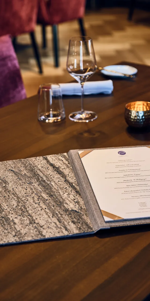 Elegant gedeckter Restauranttisch mit offener Speisekarte, Weingläsern und gefalteten Servietten