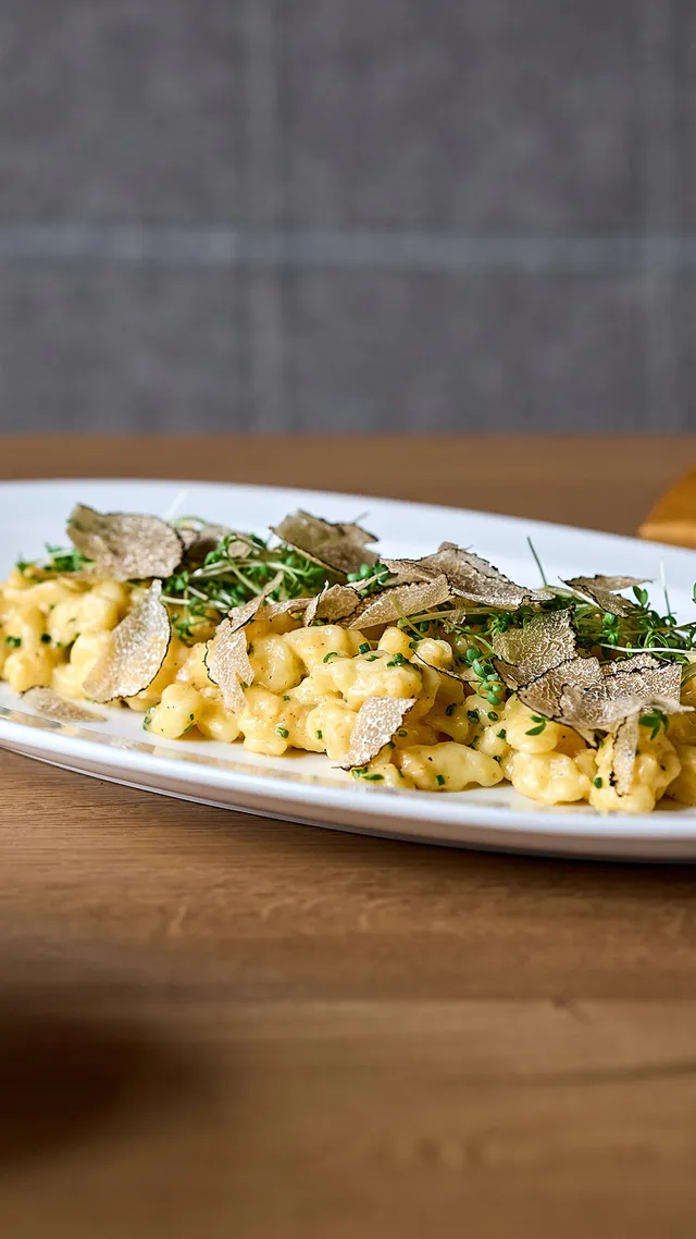 Creamy truffle spaetzle garnished with herbs on a white plate