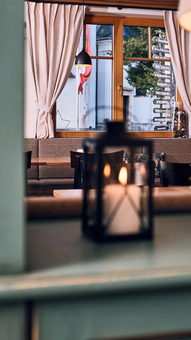 Gemütliches Restaurant mit grüner Holzverkleidung, Bärenlampe und brennenden Kerzen