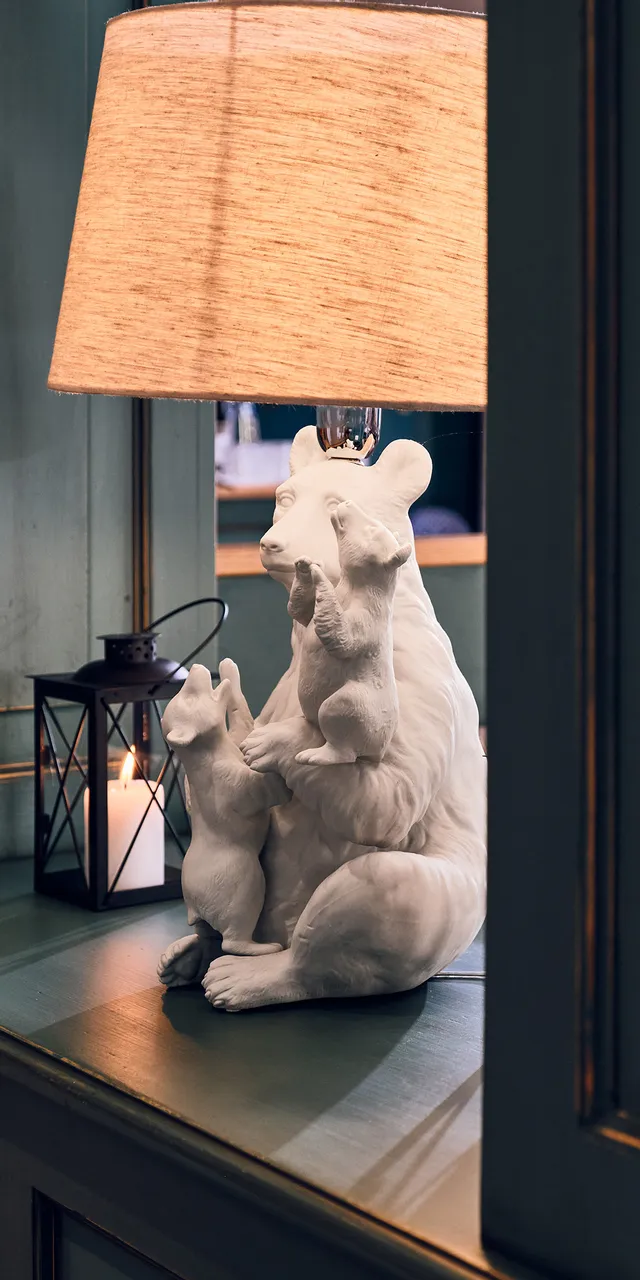 Gemütliche Inneneinrichtung mit bärenförmiger Lampe und Kerzenlaterne auf Holzregal