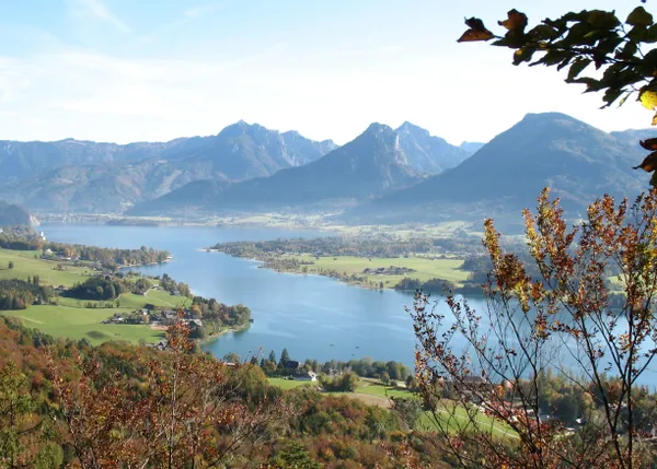 Aussicht auf den Wolfgangsee mit Alpenbergen und herbstlichem Wald in Österreich